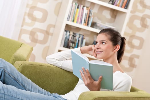 Students - Happy teenager with book sitting on armchair in lounge