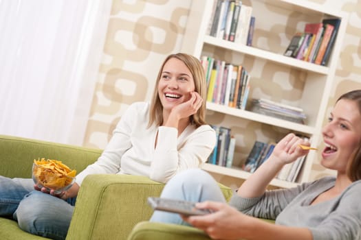 Students - Two smiling female teenager watching television in modern living room