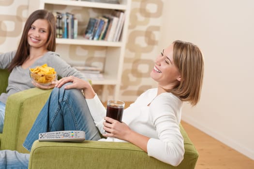 Students - Two smiling female teenager watching television together, eating crisps