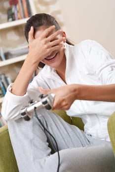Students - Female teenager playing video game holding game pad in living room
