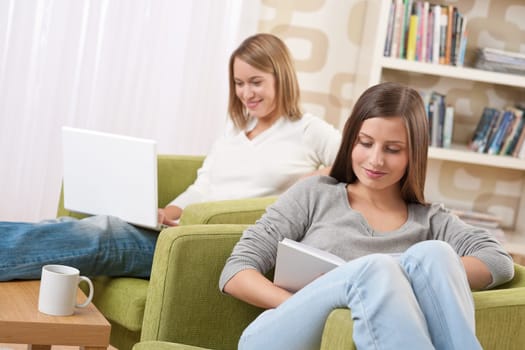 Students - Two teenage girls with laptop and book in modern lounge