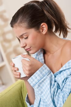 Students - Female teenager having cup of coffee, wearing pajamas in modern living room