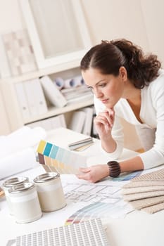 Young female interior designer at office with paint and color swatch