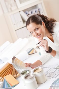 Young female interior designer at office with paint and color swatch