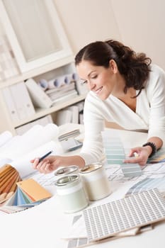 Female interior designer working at office with color swatch and paint