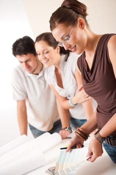 Female interior designer with two clients at office choosing colors