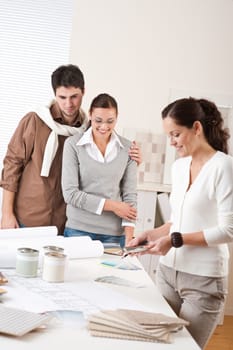 Female interior designer with two clients at office choosing colors