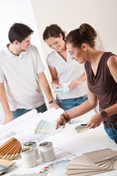 Female interior designer with two clients at office choosing colors