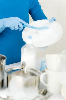 Washing dishes - hands with gloves in kitchen, housework