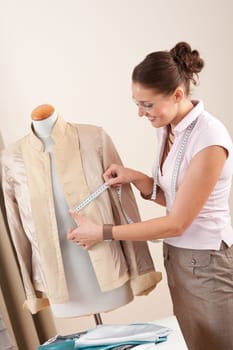 Female fashion designer taking measurement of jacket at studio