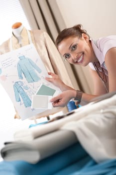 Female fashion designer working at studio with pattern cuttings and sketches