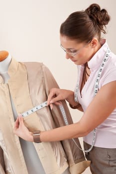 Female fashion designer taking measurement of jacket at studio