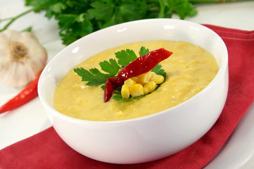 a bowl of corn soup with chili and parsley