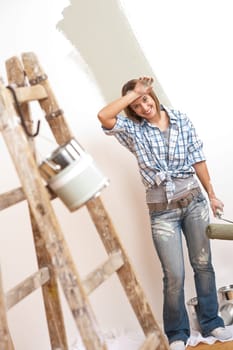 Home improvement: Cheerful woman with paint roller and ladder painting wall