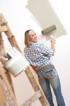 Home improvement: Blond woman painting wall with paint roller