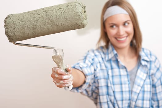 Home improvement: Young woman with paint roller painting wall