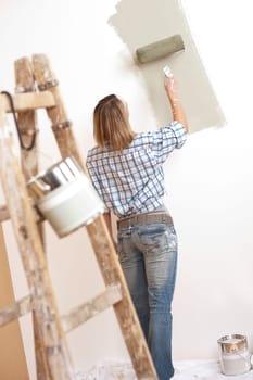 Home improvement: Blond woman painting wall with paint roller