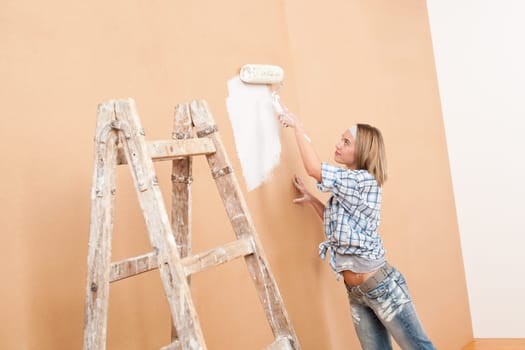 Home improvement: Woman painting wall with paint roller