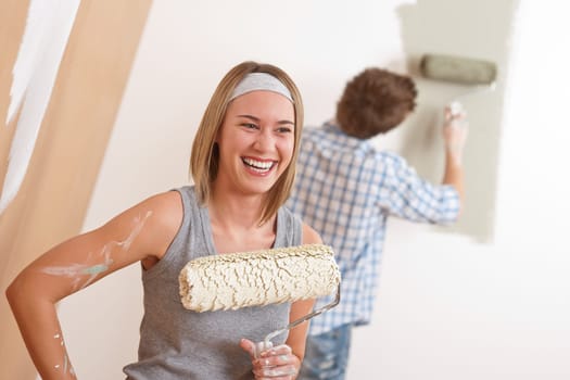 Home improvement: Young couple painting wall with paint roller
