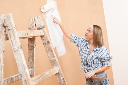 Home improvement: Woman painting wall with paint roller