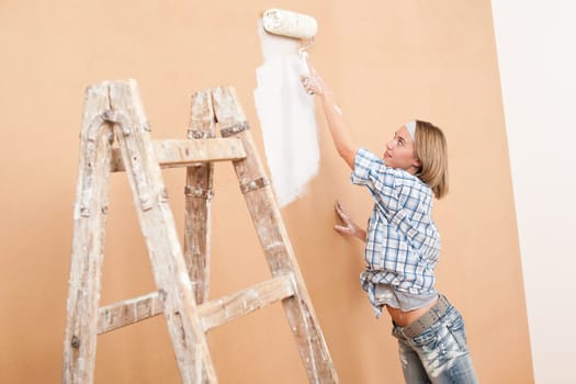 Home improvement: Woman painting wall with paint roller