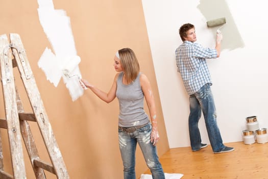 Home improvement: Young couple painting wall with paint roller