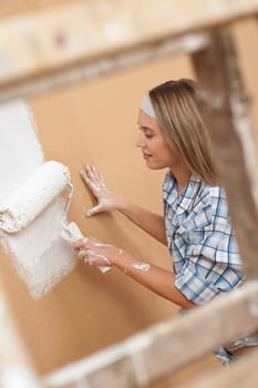 Home improvement: Woman painting wall with paint roller