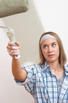 Home improvement: Young woman with paint roller painting wall