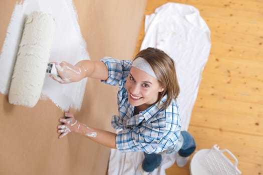 Home improvement: Young woman painting wall with paint roller