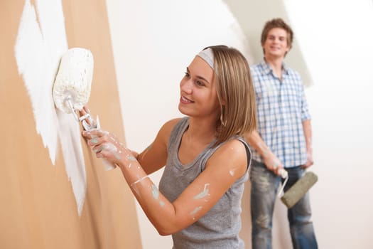 Home improvement: Young man and woman painting wall with paint roller