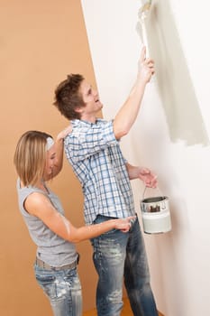 Home improvement: Man painting wall with paintbrush holding paint can