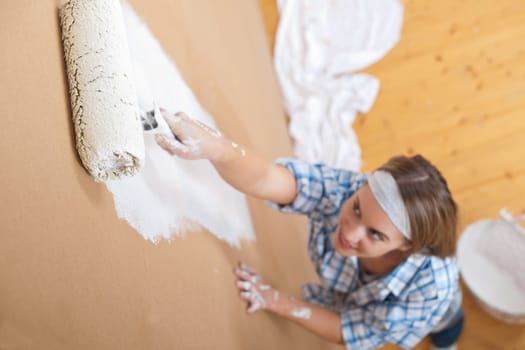 Home improvement: Young woman painting wall with paint roller