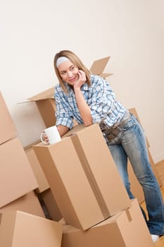 Moving house: Woman with box in new home having cup of coffee
