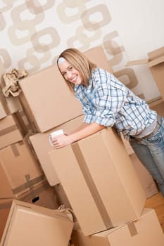 Moving house: Woman with box in new home having cup of coffee