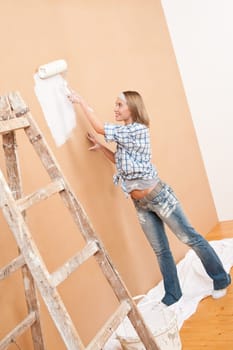 Home improvement: Woman painting wall with paint roller