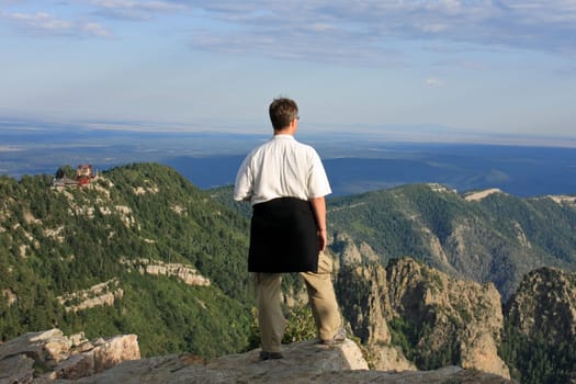 Man standing on the summit and looking down into the valley