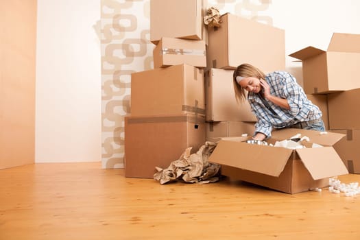 Moving house: Happy woman unpacking box in new home, kitchen, pots and pans