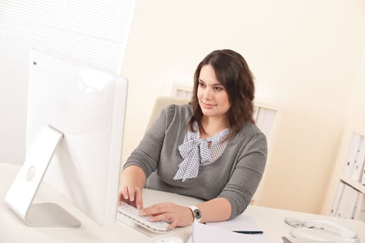 Young attractive business woman working at office with computer