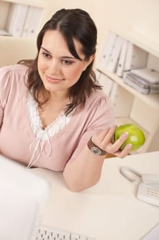 Young happy businesswoman holding apple at office having snack