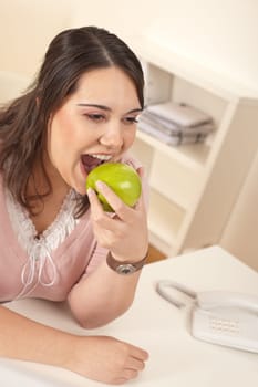 Young happy businesswoman holding apple at office having snack