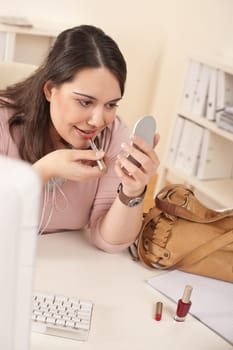 Young executive woman applying lipstick at modern office