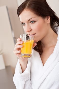 Young woman in bathrobe drink orange juice for breakfast in kitchen