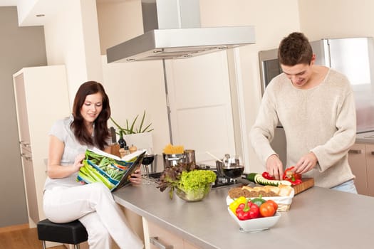 Young couple cooking in kitchen together with cookbook