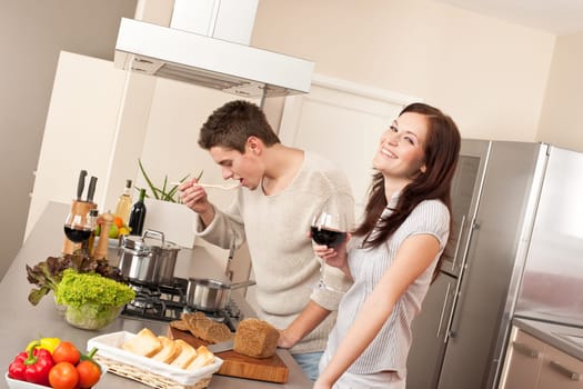 Young couple cooking in kitchen together drinking red wine