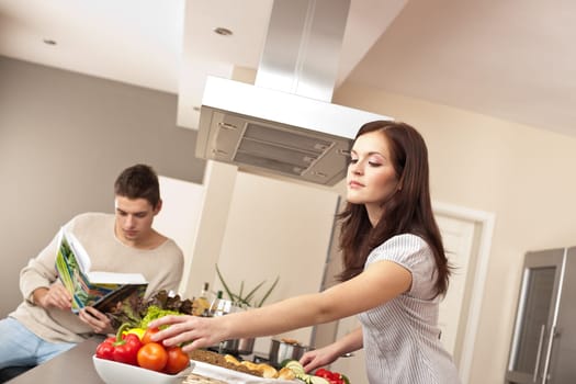 Young couple cooking in kitchen together with cookbook