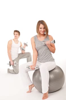 Young healthy couple training with weights and fitness ball on white