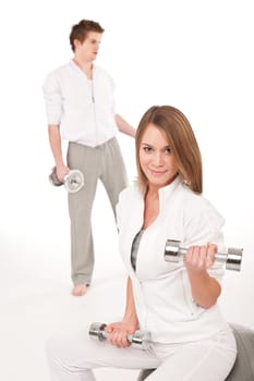 Fitness - Young healthy couple training with weights and ball on white background