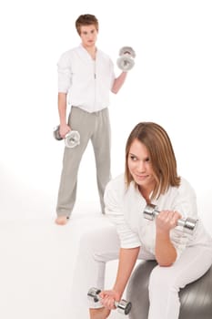 Fitness - Young healthy couple training with weights and ball on white background