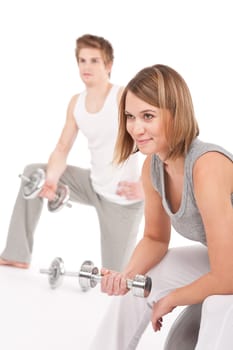 Young healthy couple training with weights and fitness ball on white