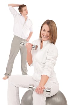Young healthy couple training with weights and fitness ball on white